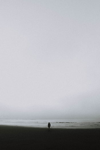 A solitary figure stands on a misty beach, evoking calm and solitude. HD phone wallpaper