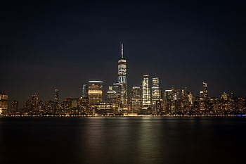 Breathtaking view of New York City's illuminated skyline reflecting on the waterfront at night. HD wallpaper