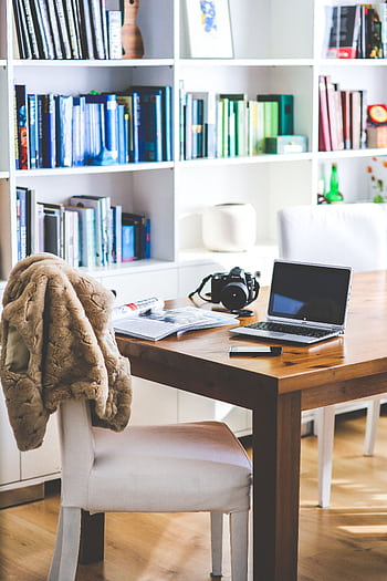 A stylish and contemporary home office setup with bookshelves, a table, and a laptop. HD phone wallpaper