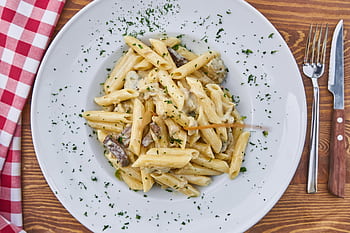 Delicious creamy penne pasta with mushrooms and parsley on a rustic table setting. HD wallpaper