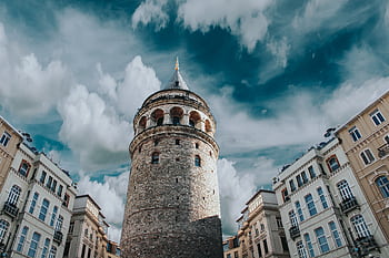 Captivating view of Galata Tower surrounded by historic architecture and dramatic clouds in Istanbul, Turkey. HD wallpaper