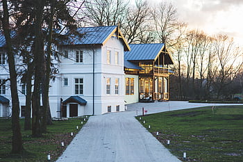 White mansion with a garden and driveway at sunset, showcasing elegant architecture. HD wallpaper