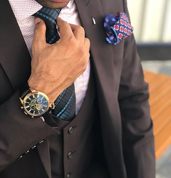 Elegant close-up of a man in a designer suit adjusting his tie, showcasing luxury fashion. HD phone wallpaper