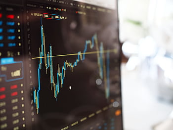 Detailed view of financial trading graphs on a monitor, illustrating stock market trends. HD wallpaper