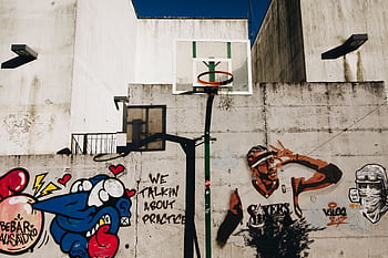 Urban basketball hoop with vibrant street art on a sunny day in Porto, Portugal. HD wallpaper