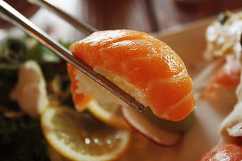 Mouthwatering salmon nigiri sushi held by chopsticks, ready to eat. HD wallpaper
