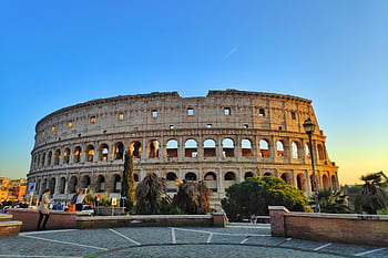 Vibrant of the Roman Colosseum at sunset, capturing its historic architecture in Rome, Italy. HD wallpaper