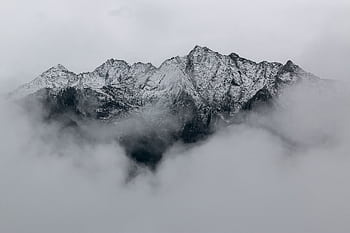 A breathtaking view of snow-covered mountain peaks surrounded by dense fog, creating a mystical landscape. HD wallpaper