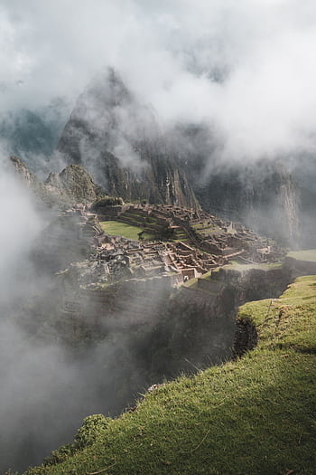 A breathtaking view of Machu Picchu surrounded by mist and mountains in Peru. HD phone wallpaper