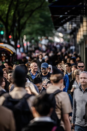A bustling urban scene with diverse people walking on a tree-lined city street. HD phone wallpaper