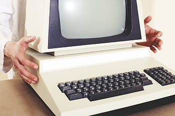 A vintage computer with a classic CRT monitor and keyboard, being held by hands. HD wallpaper