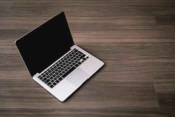 Sleek open laptop placed on a polished wooden floor, showcasing modern technology design. HD wallpaper
