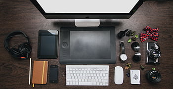 Organized workspace with tech devices and accessories on a wooden desk. HD wallpaper