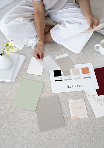 Designer sits on carpet with color palettes and samples, planning creative project. HD phone wallpaper