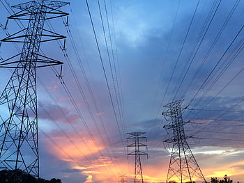 A scenic view of high voltage power lines silhouetted against a vibrant sunset sky. HD wallpaper