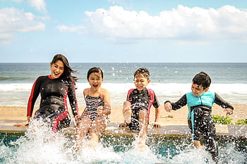 A family having fun splashing water near the seashore on a sunny day in Bali, Indonesia. HD wallpaper