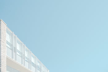 Low angle view of a modern building facade against a blue sky in London, Ontario. HD wallpaper