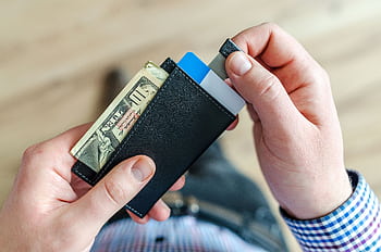 Close-up of a man's hands holding a wallet with cash and credit cards, indicating financial management. HD wallpaper