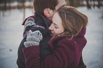 A couple warmly embraces outdoors in a winter scene, showcasing affection and joy. HD wallpaper