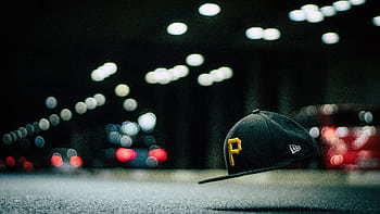 A levitating cap with letter 'P' floats above asphalt, surrounded by night street bokeh lights. HD wallpaper