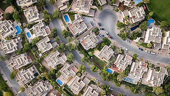 Explore a stunning aerial view of a residential area in Dubai with lush greenery and swimming pools. HD wallpaper