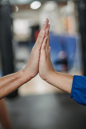 Two hands giving a high five, symbolizing teamwork and success, indoors. HD phone wallpaper