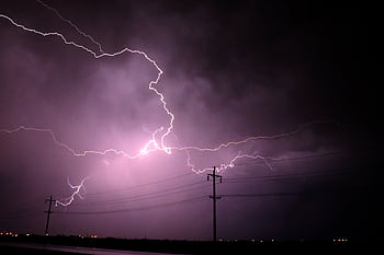 Stunning lightning bolts illuminate a stormy night sky over silhouetted power lines. HD wallpaper