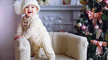 Beautiful Smiling Cute Baby Is Standing On Couch Near Decorated Christmas Tree Wearing Woolen Knitted Dress And Cap Cute HD wallpaper