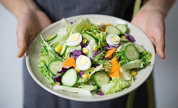 Freshly prepared salad with cucumber, lettuce, carrots, and egg slices presented on a plate. HD wallpaper