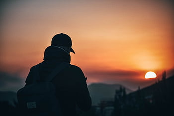 A person silhouetted during sunset in a scenic mountain landscape, capturing the essence of outdoor adventure and travel. HD wallpaper