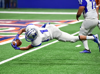 Football player making an incredible diving catch during a high-energy game in the stadium. HD wallpaper