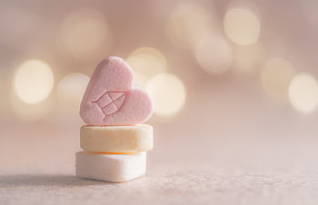 Close-up of heart-shaped candy with a warm bokeh background, perfect for holiday themes. HD wallpaper