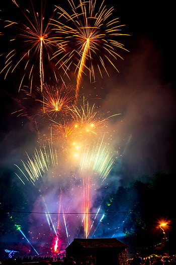 A stunning display of colorful fireworks illuminating the night sky at a lively celebration. HD phone wallpaper