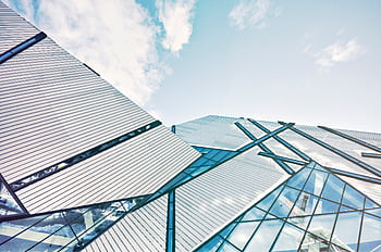 Low angle shot of a contemporary building with glass panel facades against a cloudy sky. HD wallpaper