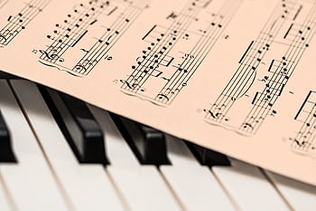 Black and white piano keys with a sheet of classical music creating a harmonious composition. HD wallpaper