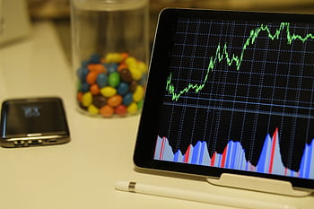 Tablet display of stock market data with smart and colorful candies on desk. HD wallpaper