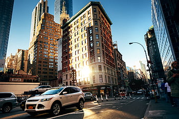A bustling New York City street with towering buildings at golden hour, capturing urban life. HD wallpaper