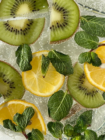 Vibrant citrus and kiwi slices with mint leaves in a sparkling beverage viewed from above. HD phone wallpaper
