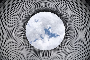 Modern architectural tunnel with a geometric pattern revealing a bright sky. HD wallpaper