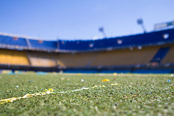 Close-up view of a vibrant football pitch in a sunlit Buenos Aires stadium, perfect for sports enthusiasts. HD wallpaper