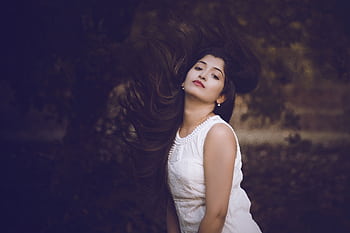 Striking portrait of a woman with flowing hair wearing a white dress in a natural setting. HD wallpaper