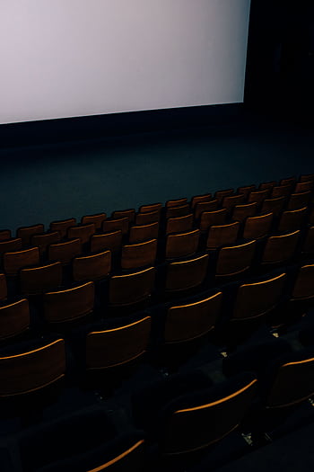 A dark and empty theater auditorium with rows of seats and a large screen. HD phone wallpaper