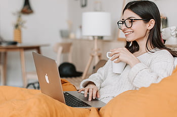 Woman enjoying a cozy moment with a laptop and coffee in a modern interior setting. HD wallpaper