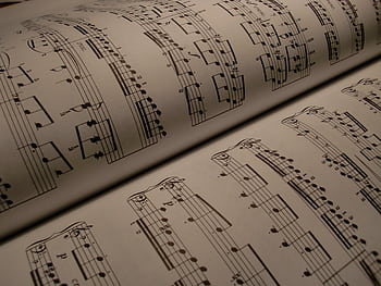 Detailed view of an open music book displaying musical notes and sheet music. HD wallpaper