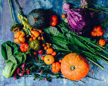 A vibrant assortment of fresh vegetables including pumpkins, cabbage, and tomatoes on a rustic surface. HD wallpaper