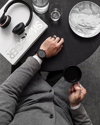 Top view of a man holding coffee in a stylish setup with heads and magazine. HD phone wallpaper