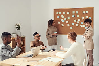 A diverse group of professionals collaborating in a modern office setting with a brainstorming session. HD wallpaper