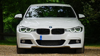 Elegant white luxury car with prominent grille and sleek design, set outdoors, showcasing modern headlights. HD wallpaper