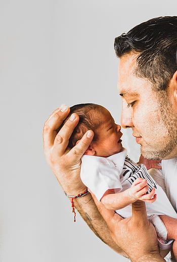 A touching portrait of a father gently holding his newborn baby, showcasing love and fatherhood. HD phone wallpaper