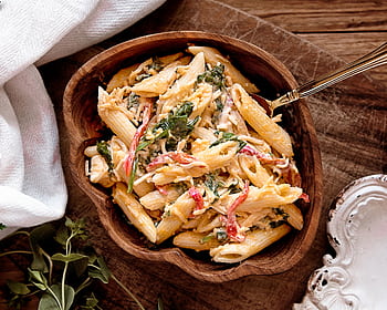 A mouth-watering creamy pasta salad with fresh vegetables served in a rustic wooden bowl. HD wallpaper